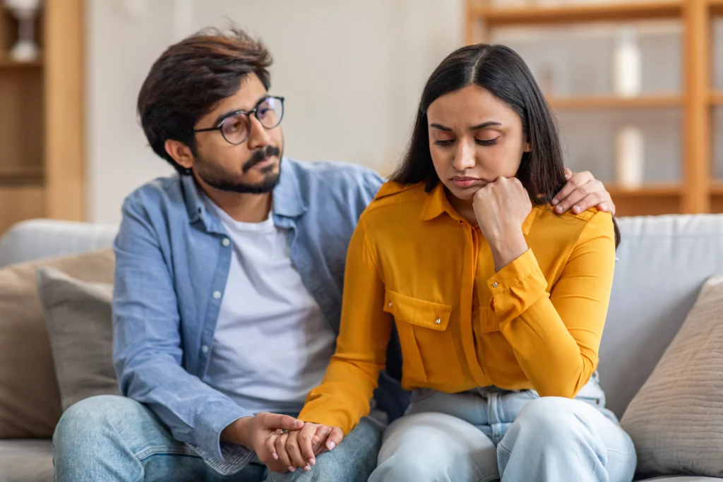 Home V2 19 Man comforting woman on sofa while discussing visa overstay and marriage green card concerns