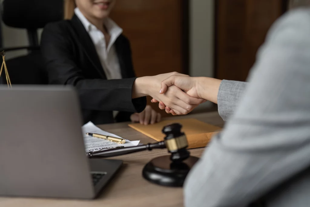 Home V2 17 Two business professionals shaking hands over legal documents with a gavel during a federal litigation consultation
